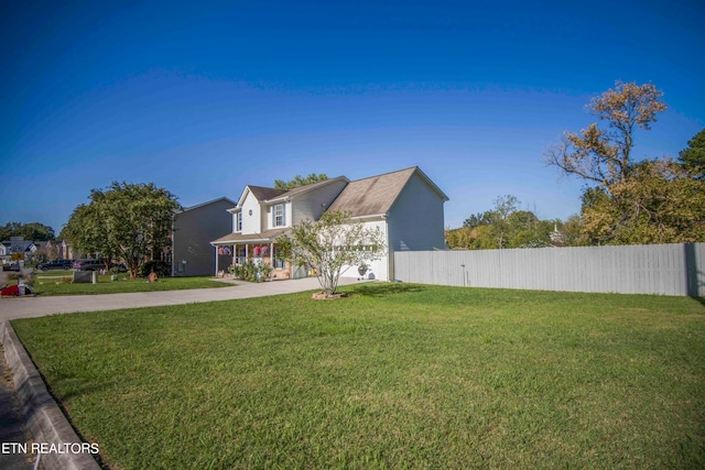 view of front of house with concrete driveway, a front yard, and fence