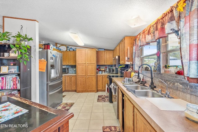 kitchen featuring light tile patterned floors, sink, a textured ceiling, stainless steel appliances, and vaulted ceiling