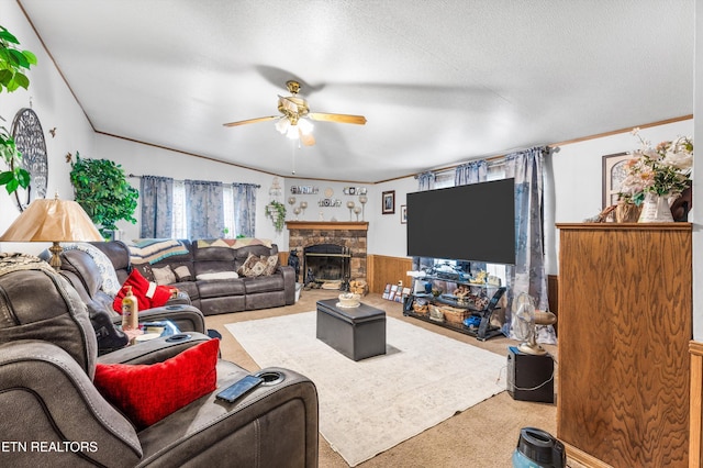 carpeted living room with wood walls, a textured ceiling, ceiling fan, and a stone fireplace