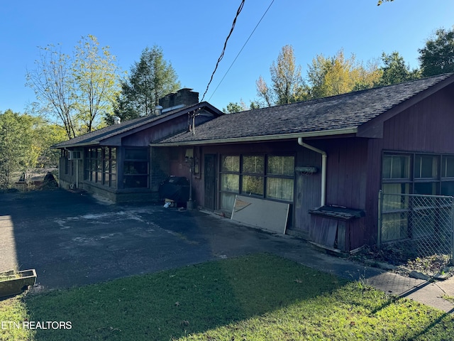 back of property featuring a yard, a patio area, and a sunroom