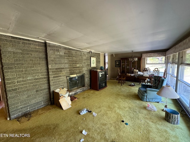 carpeted living room featuring a notable chandelier and a brick fireplace