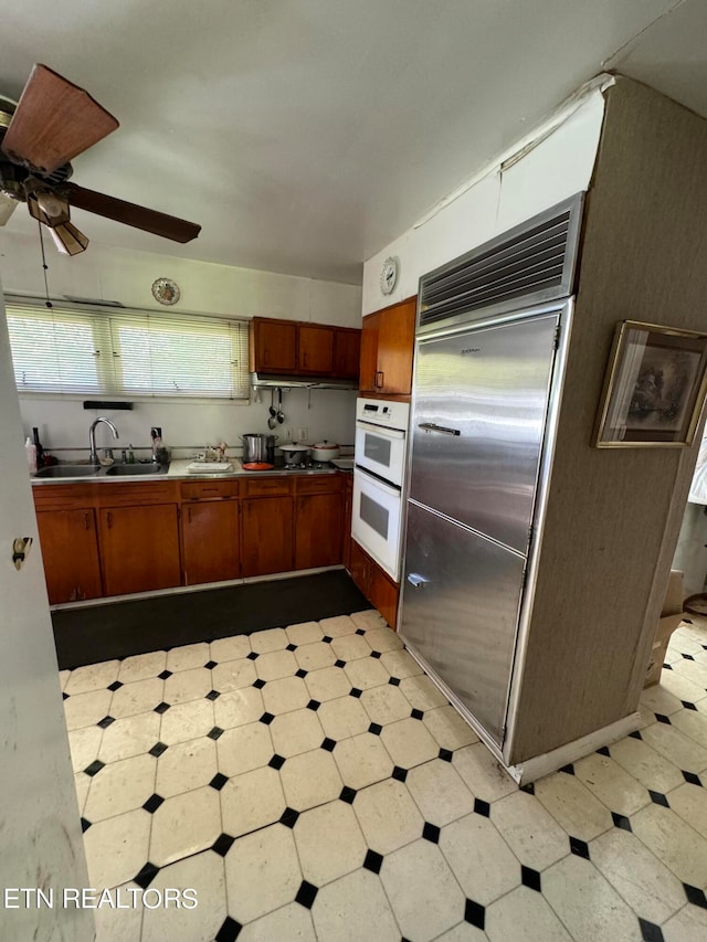 kitchen featuring ceiling fan, white double oven, sink, and built in fridge