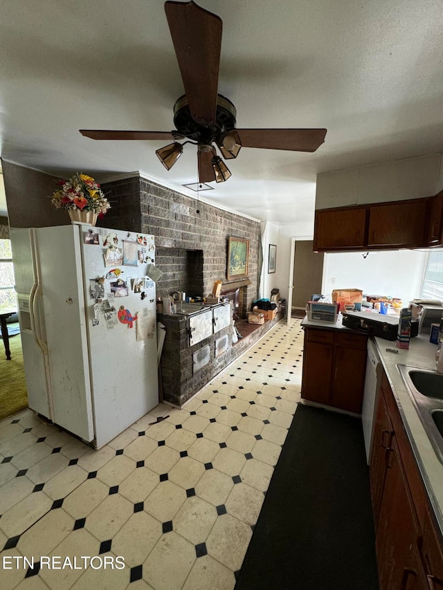 kitchen with white appliances, sink, ceiling fan, and brick wall