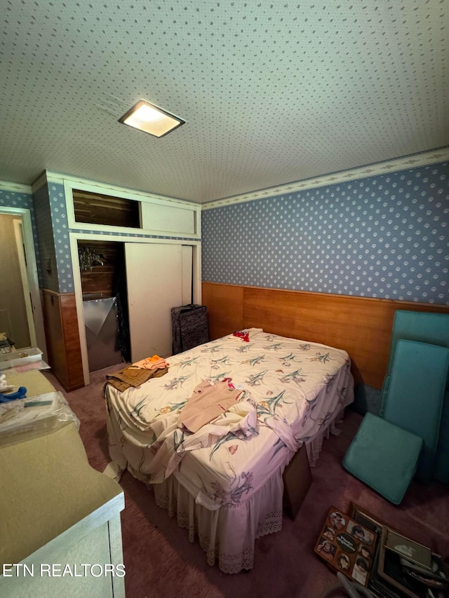 carpeted bedroom with a closet, wood walls, and crown molding