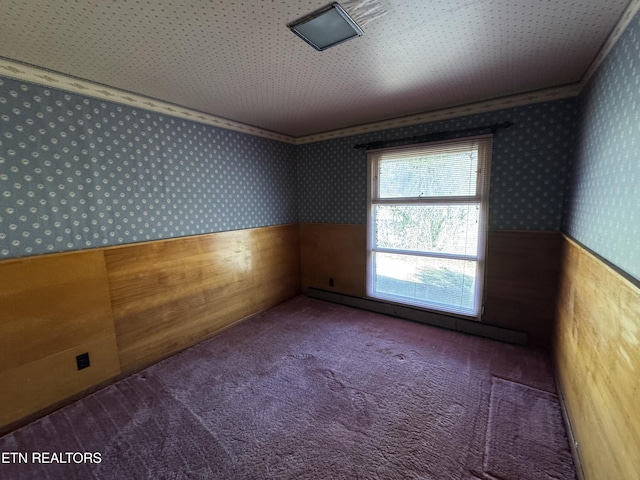 empty room featuring a baseboard heating unit, crown molding, and carpet flooring