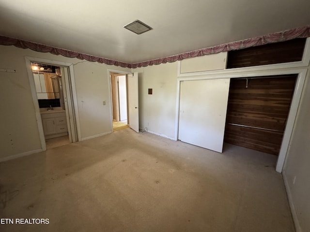 unfurnished bedroom featuring light carpet, sink, connected bathroom, and a closet