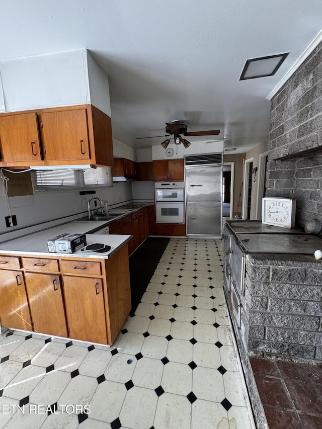 kitchen featuring double oven, ceiling fan, sink, and built in fridge