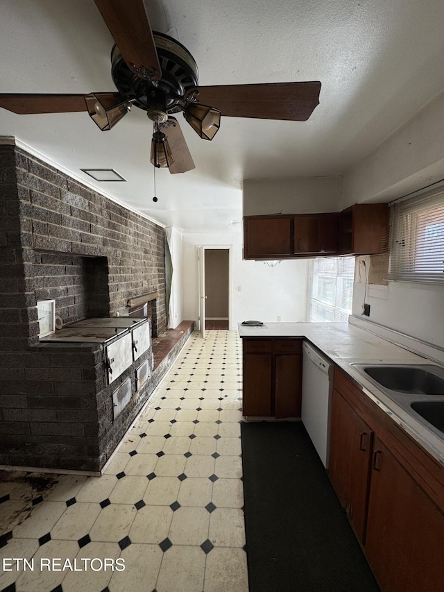 kitchen with sink, dishwasher, kitchen peninsula, ceiling fan, and brick wall