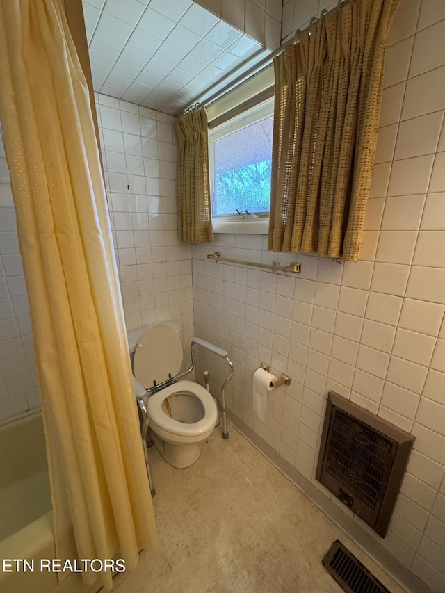 bathroom with heating unit, toilet, tile walls, and shower / bath combo with shower curtain