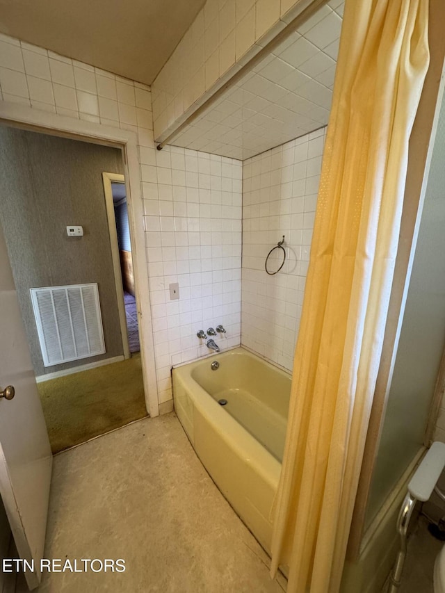 bathroom with tile walls, shower / tub combo, and toilet