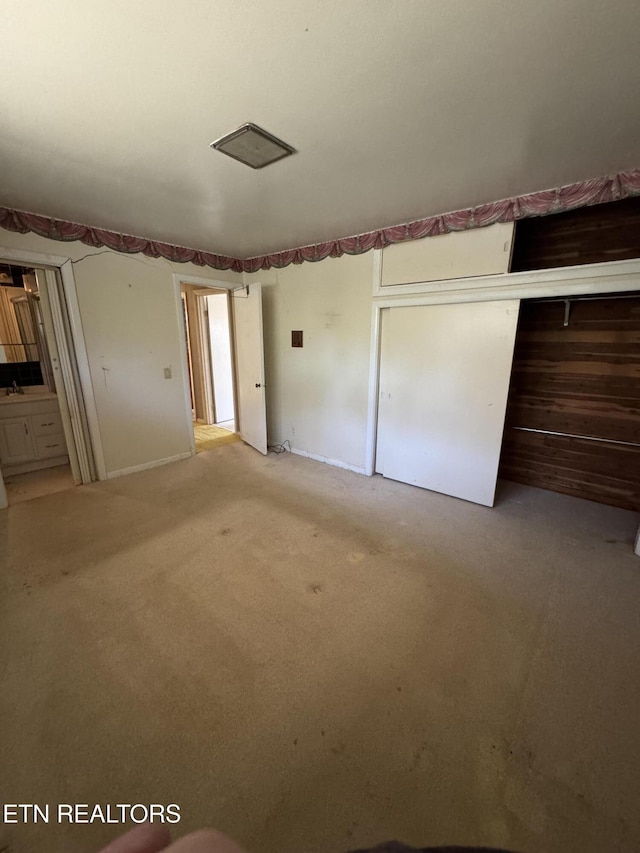 unfurnished bedroom with a closet and light carpet