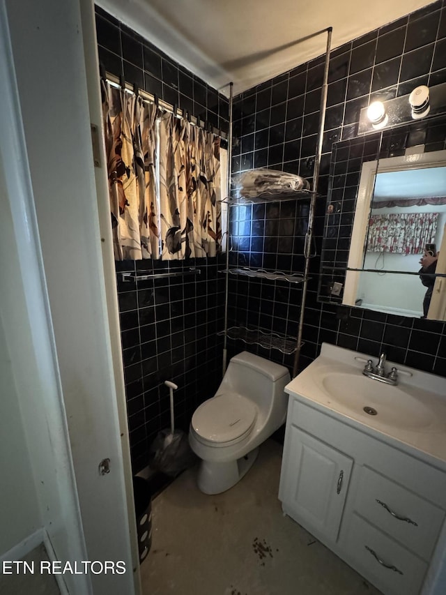 bathroom with tile walls, vanity, toilet, and walk in shower