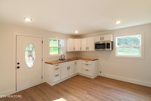 kitchen with white cabinetry, butcher block countertops, and a healthy amount of sunlight