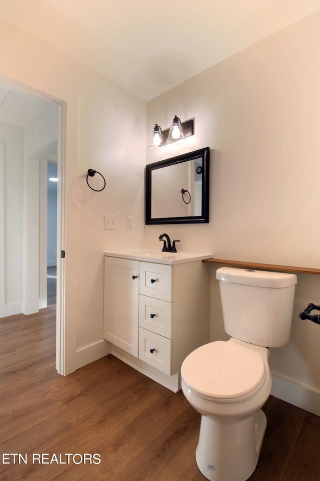 bathroom with wood-type flooring, vanity, and toilet