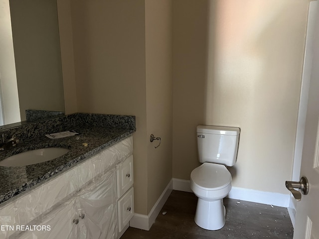 bathroom featuring vanity, toilet, and baseboards