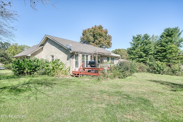 rear view of house with a wooden deck and a lawn