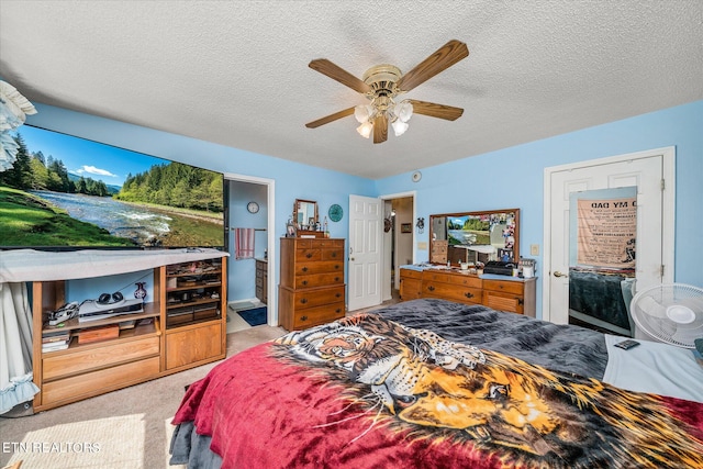 carpeted bedroom with ensuite bath, ceiling fan, and a textured ceiling