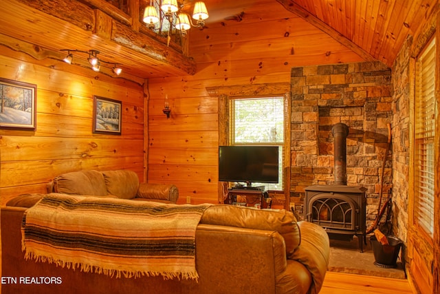 living room featuring wooden walls, wood ceiling, a wood stove, light hardwood / wood-style flooring, and vaulted ceiling with beams