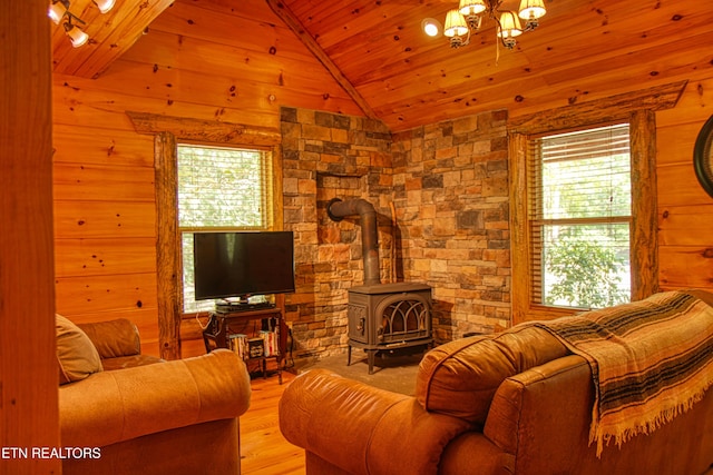 living room with wood ceiling, wood walls, a wood stove, high vaulted ceiling, and light wood-type flooring