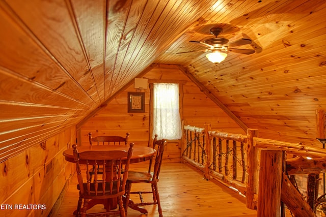 dining room with wooden walls, vaulted ceiling, wooden ceiling, and light hardwood / wood-style flooring