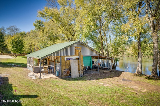 view of outdoor structure featuring a water view and a lawn