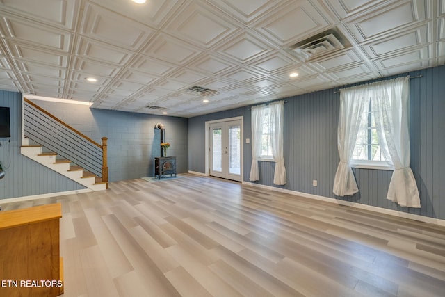 basement with a wood stove, french doors, wood-type flooring, and plenty of natural light