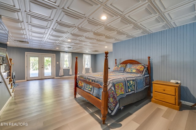 bedroom featuring access to outside, french doors, coffered ceiling, wooden walls, and light hardwood / wood-style flooring