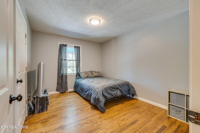 bedroom with light hardwood / wood-style floors and a textured ceiling