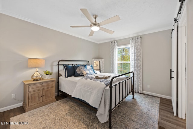 bedroom featuring dark hardwood / wood-style flooring, ceiling fan, crown molding, and a barn door