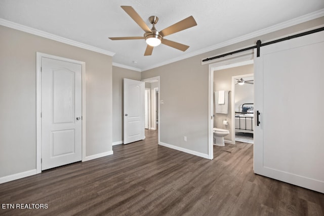 unfurnished bedroom featuring a barn door, ensuite bathroom, dark hardwood / wood-style flooring, ornamental molding, and ceiling fan