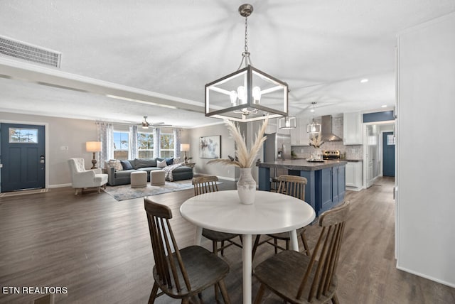 dining area with ceiling fan with notable chandelier, crown molding, and dark hardwood / wood-style floors