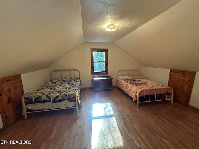 bedroom with vaulted ceiling, a textured ceiling, and dark wood-type flooring