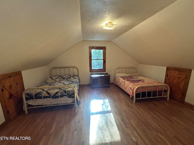 bedroom featuring lofted ceiling, a textured ceiling, and dark hardwood / wood-style flooring