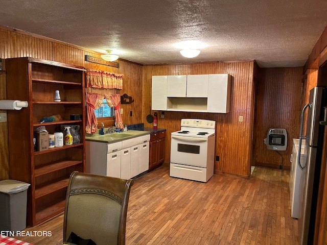 kitchen featuring heating unit, white cabinets, wood walls, white electric range oven, and light wood-type flooring