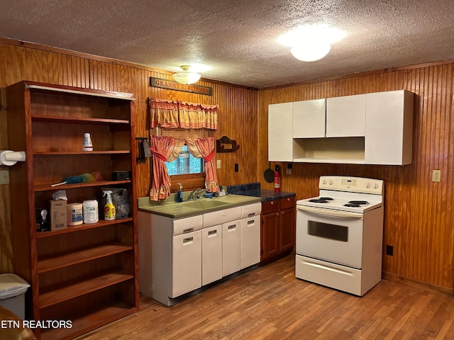 kitchen featuring wooden walls, light wood-type flooring, white electric stove, and white cabinetry