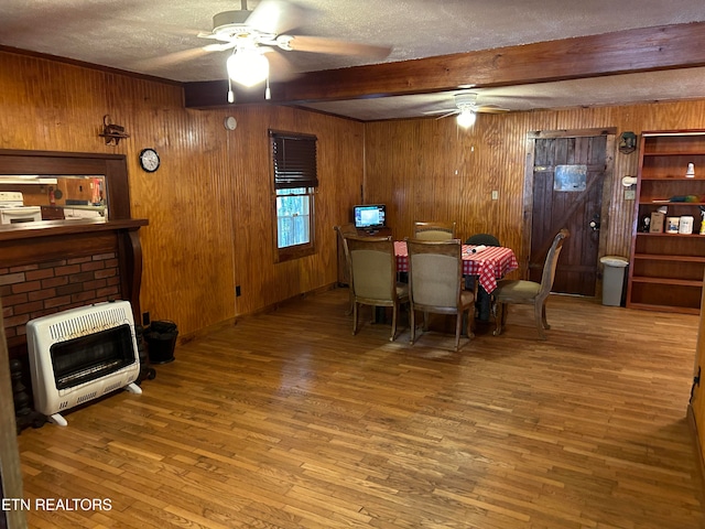 dining area featuring heating unit, wood walls, beamed ceiling, and hardwood / wood-style floors