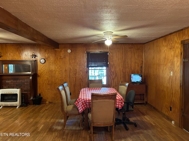 dining area featuring ceiling fan, hardwood / wood-style flooring, heating unit, and a textured ceiling