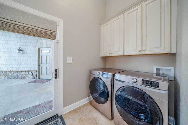 clothes washing area featuring cabinets, light tile patterned floors, and washing machine and dryer