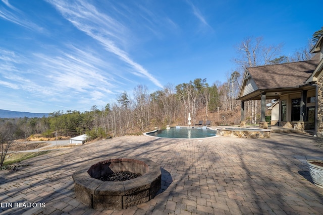 view of pool with an in ground hot tub, a patio area, and a fire pit