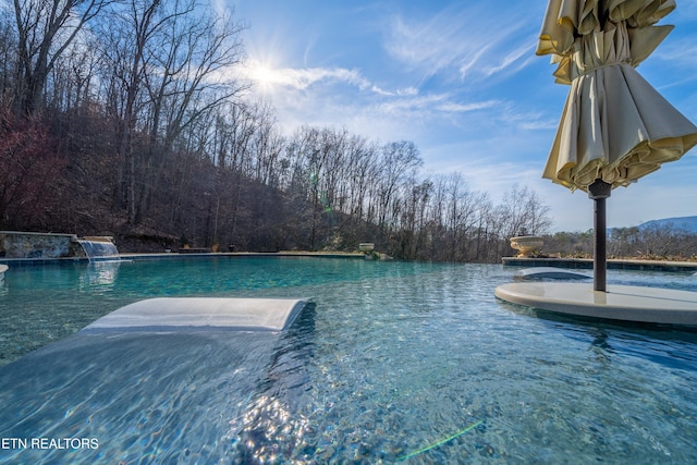 view of swimming pool with a water view and pool water feature