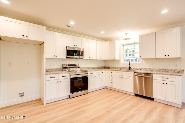 kitchen featuring light hardwood / wood-style flooring, sink, stainless steel appliances, light stone countertops, and white cabinetry