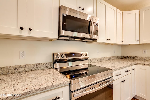 kitchen featuring white cabinets, appliances with stainless steel finishes, and light stone counters