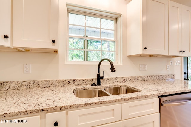 kitchen with light stone counters, sink, stainless steel dishwasher, and white cabinetry