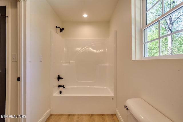 bathroom with wood-type flooring, bathtub / shower combination, and toilet