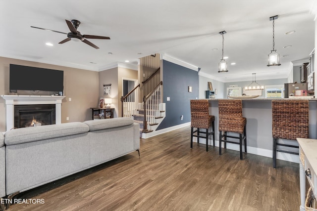 living room with ceiling fan with notable chandelier, crown molding, and dark hardwood / wood-style flooring