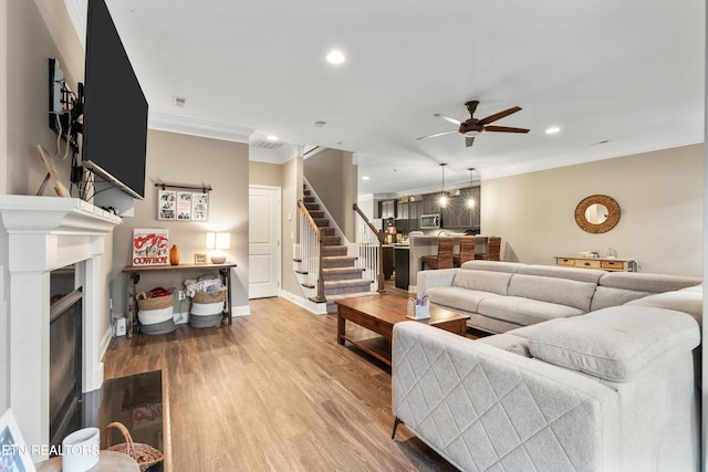 living room with crown molding, hardwood / wood-style floors, and ceiling fan