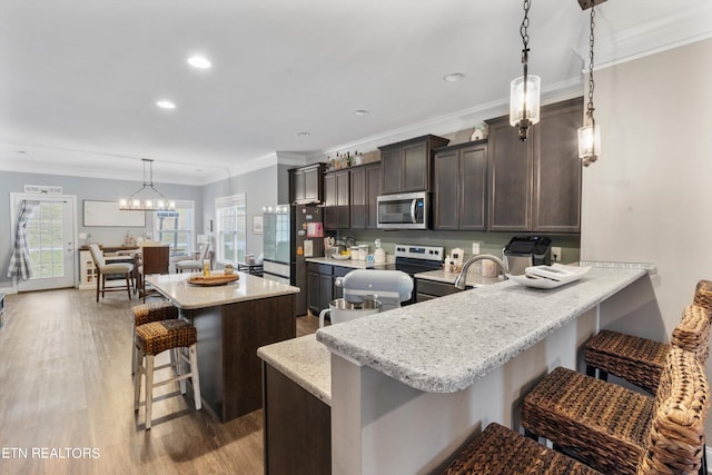 kitchen featuring light wood-type flooring, pendant lighting, a breakfast bar area, stainless steel appliances, and kitchen peninsula