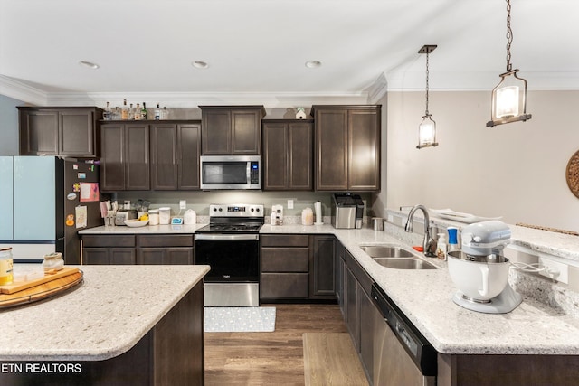 kitchen featuring dark wood-type flooring, decorative light fixtures, sink, stainless steel appliances, and ornamental molding