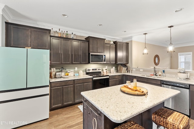 kitchen featuring sink, stainless steel appliances, hanging light fixtures, ornamental molding, and a center island