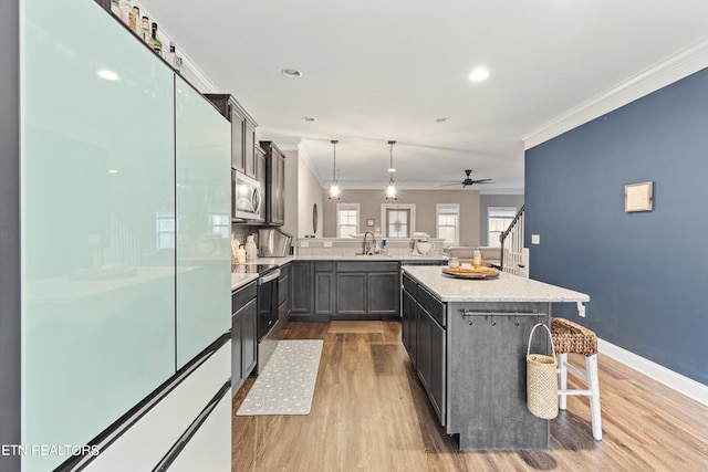 kitchen featuring a breakfast bar area, stainless steel appliances, kitchen peninsula, hanging light fixtures, and ornamental molding